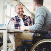 A man in a lighthearted conversation with another man with using a mobility aid