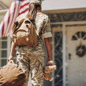 A uniformed soldier walking towards a home